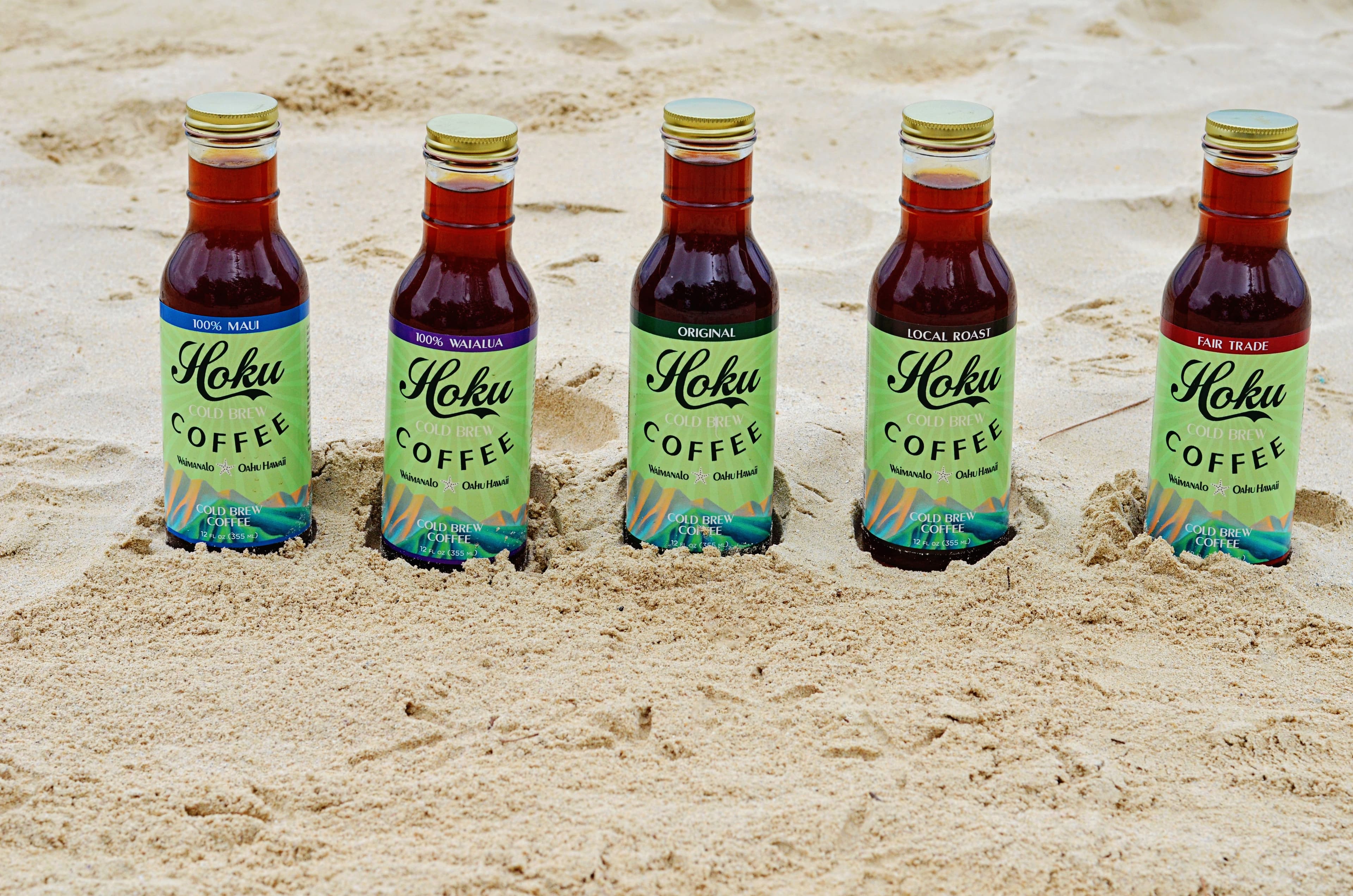 Hoku Cold Brew bottles in beach sand